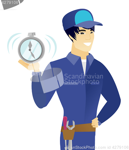 Image of Young asian mechanic holding alarm clock.