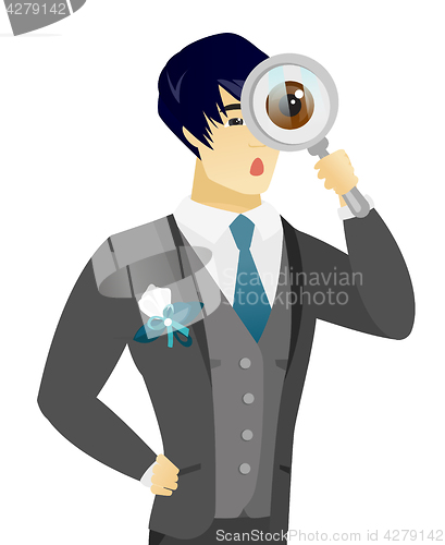 Image of Young asian groom with magnifying glass.