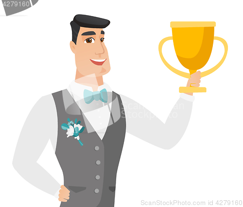 Image of Young caucasian groom holding a trophy.