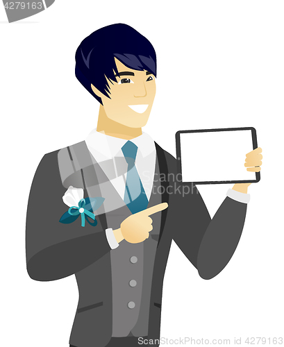 Image of Young asian groom holding tablet computer.
