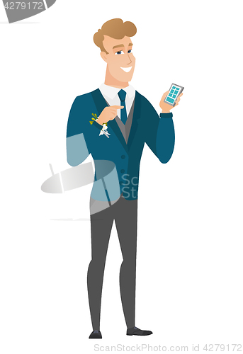 Image of Caucasian groom holding a mobile phone.