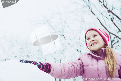 Image of Happy little girl playing  on winter snow day.