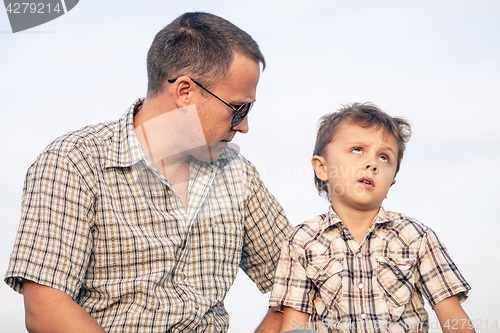 Image of Father and son playing on the field at the day time.