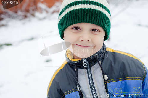 Image of Happy little boy playing  on winter snow day.