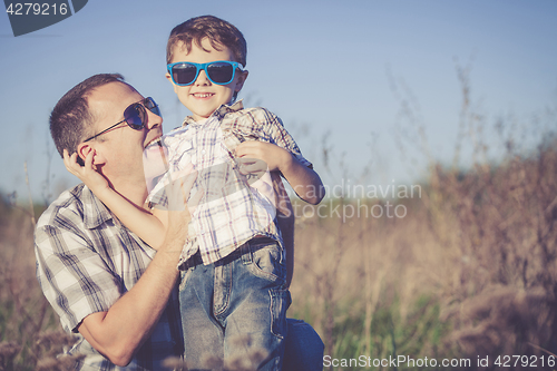 Image of Father and son playing on the field at the day time.