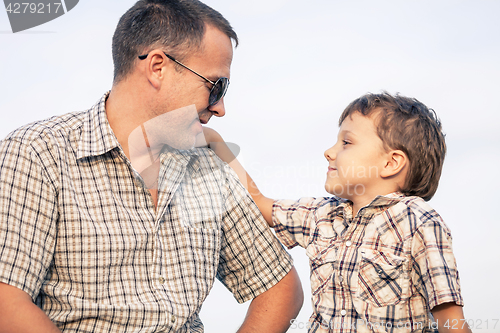 Image of Father and son playing on the field at the day time.