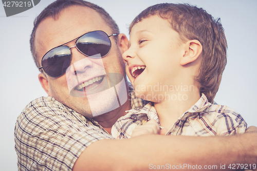 Image of Father and son playing on the beach at the sunset time.