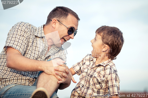 Image of Father and son playing on the field at the day time.