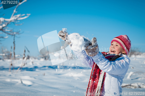 Image of Happy little girl playing  on winter snow day.