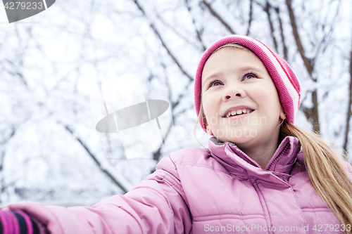 Image of Happy little girl playing  on winter snow day.