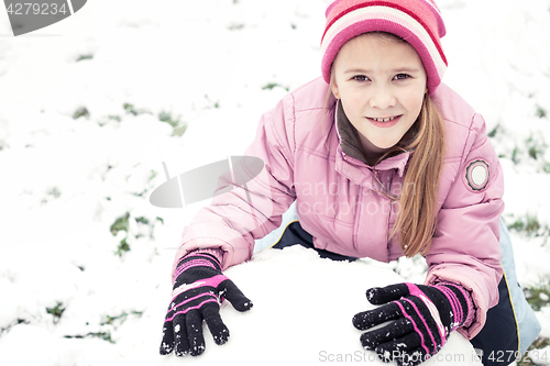 Image of Happy little girl playing  on winter snow day.