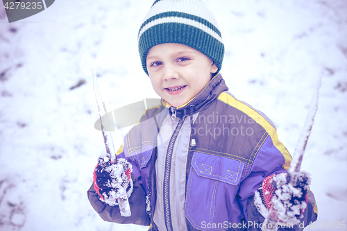 Image of Happy little boy playing  on winter snow day.