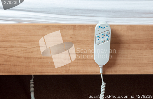 Image of Bed remote hanging at the side from a bed