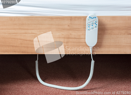 Image of Bed remote hanging at the side from a bed