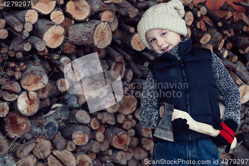 Image of Little boy chopping firewood in the front yard at the day time.