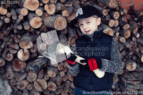 Image of Little boy chopping firewood in the front yard at the day time.