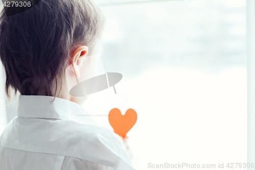 Image of sad little boy sitting near the window