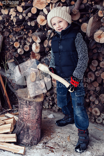 Image of Little boy chopping firewood in the front yard at the day time.