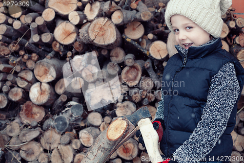 Image of Little boy chopping firewood in the front yard at the day time.