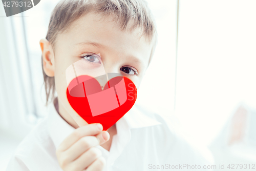 Image of One little boy standing near a window. 