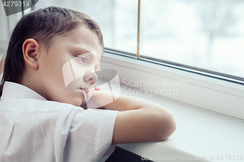 Image of sad little boy sitting near the window