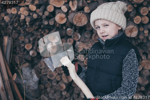 Image of Little boy chopping firewood in the front yard at the day time.