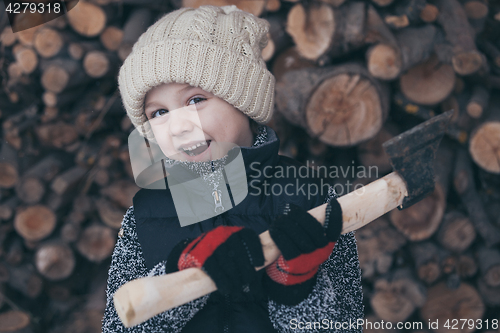 Image of Little boy chopping firewood in the front yard at the day time.