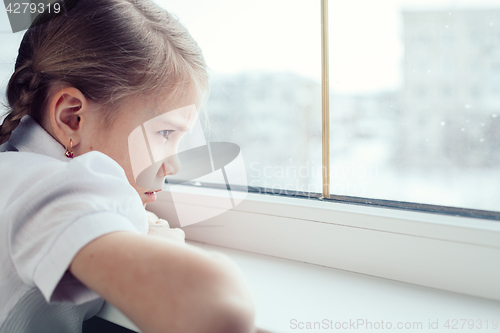 Image of sad little girl sitting near the window