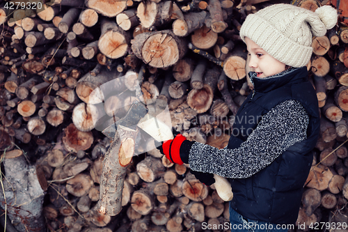 Image of Little boy chopping firewood in the front yard at the day time.