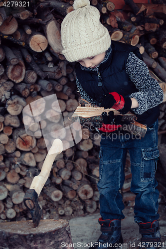 Image of Little boy chopping firewood in the front yard at the day time.