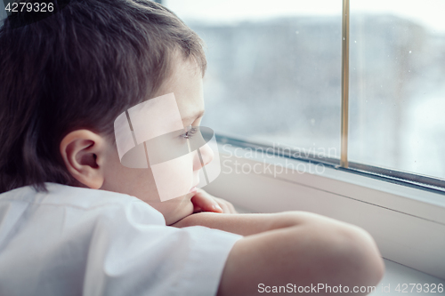 Image of sad little boy sitting near the window