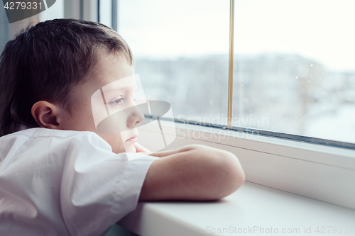 Image of sad little boy sitting near the window