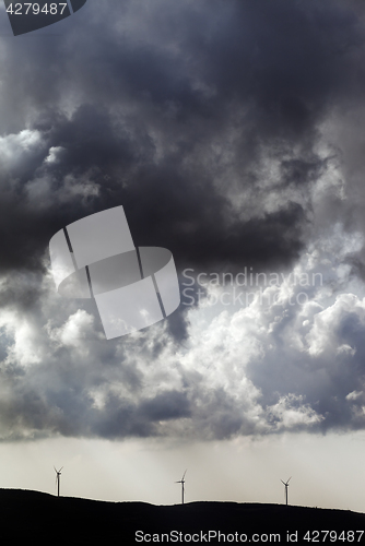 Image of Silhouette of wind farm and cloudy sky before storm