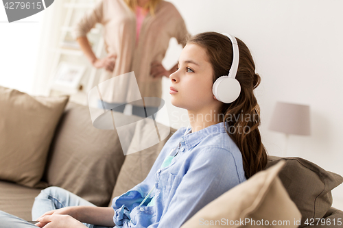 Image of girl with earphones and angry mother at home