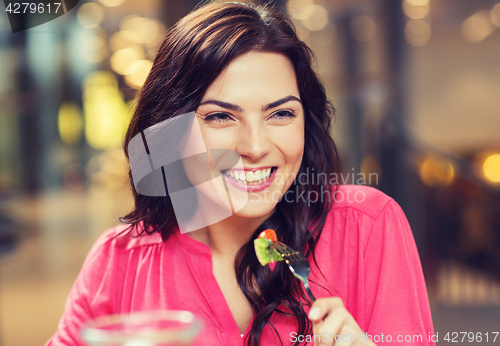 Image of happy young woman having dinner at restaurant