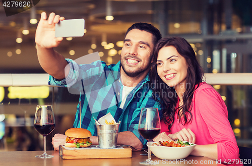 Image of couple taking selfie by smartphone at restaurant