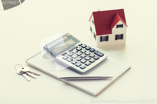 Image of close up of home model, calculator and notebook