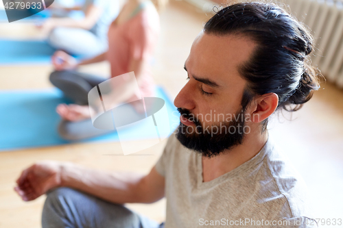 Image of man with group of people meditating at yoga studio