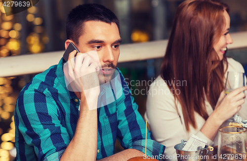 Image of man with smartphone and friends at restaurant