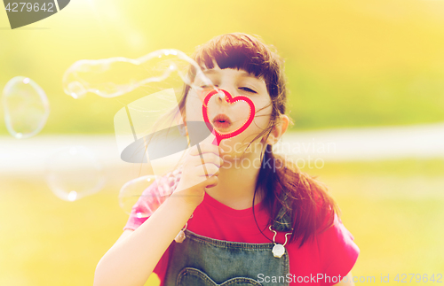 Image of little girl blowing soap bubbles outdoors