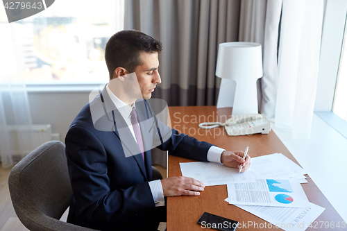 Image of businessman with papers working at hotel room