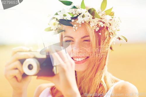 Image of happy woman with film camera in wreath of flowers