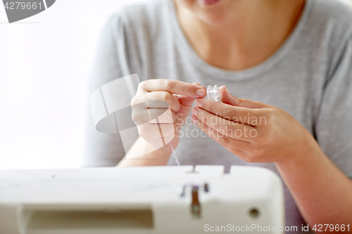 Image of woman with spool of thread and sewing machine