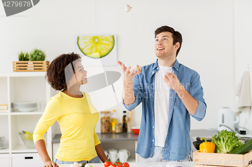 Image of couple cooking food and juggling garlic at home