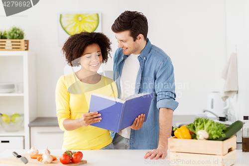 Image of happy couple with cooking book at home kitchen