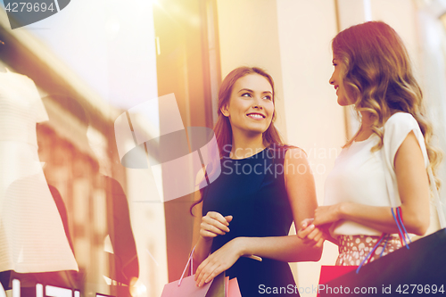 Image of happy women with shopping bags at shop window