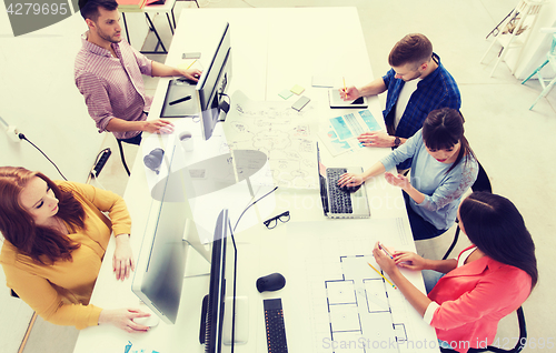 Image of creative team with computers, blueprint at office