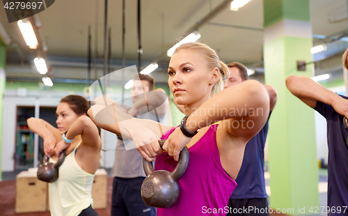 Image of group of people with kettlebells exercising in gym