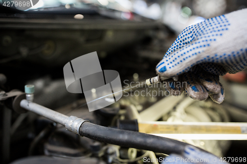 Image of mechanic with dipstick checking motor oil level