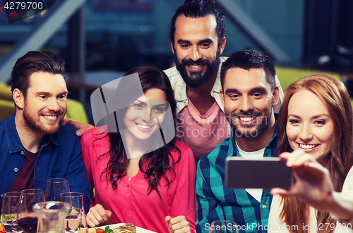 Image of friends taking selfie by smartphone at restaurant